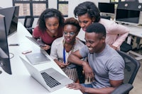 a group of people looking at a laptop in an office